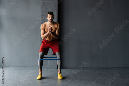 Young shirtless sportsman doing exercise with expander stretch tape © Drobot Dean