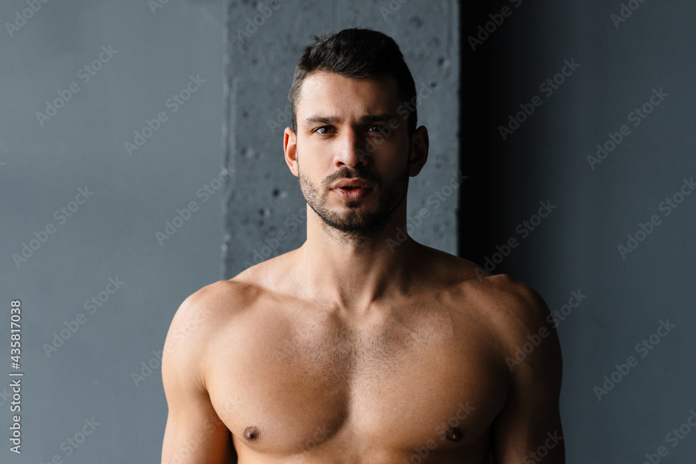 Young shirtless sportsman looking at camera while working out indoors Young shirtless sportsman looking at camera while working out indoors
