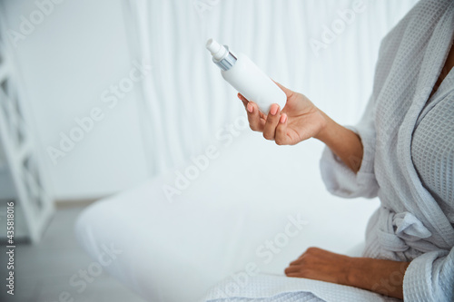 Female in a waffle weave bathrobe holding a new skincare product