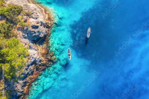 Aerial view of people on floating sup boards on blue sea, rocks, trees at sunset in summer. Blue lagoon, Oludeniz, Turkey. Tropical landscape. Kayaks on clear water. Active travel. Top view of canoe © den-belitsky
