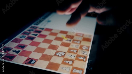 a man plays chess on a tablet at night