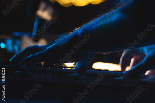 A keyboard player plays a synthesizer in the spotlight