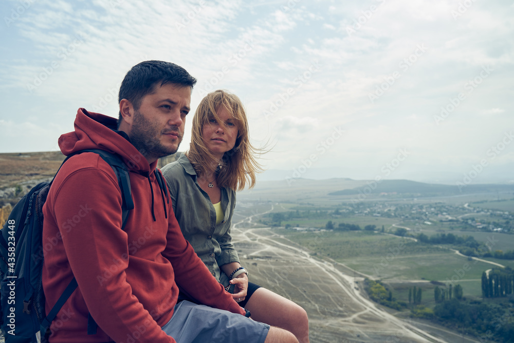 Couple is sitting on the stones, resting, enjoying the view and the fresh air. Couple is sitting on the stones, resting, enjoying the view and the fresh air.