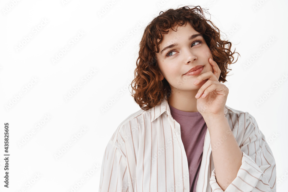Thoughtful attractive woman looking left at product banner and thinking, touching face as if pondering, making choice in shop, standing in casual clothes in relaxed pose against white background Thoughtful attractive woman looking left at product banner and thinking, touching face as if pondering, making choice in shop, standing in casual clothes in relaxed pose against white background