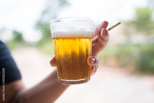 Mulher segurando um copo de cerveja e um cigarro de palha photo