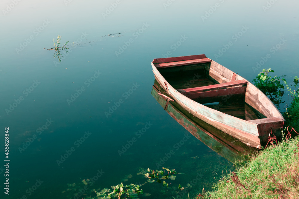 Boat full of water . Wooden fishing old boat moored on the shore