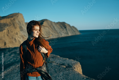 woman travels on nature in the mountains with a backpack near the sea
