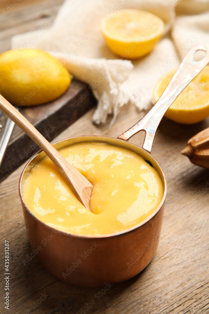Delicious lemon curd in saucepan on wooden table Delicious lemon curd in saucepan on wooden table