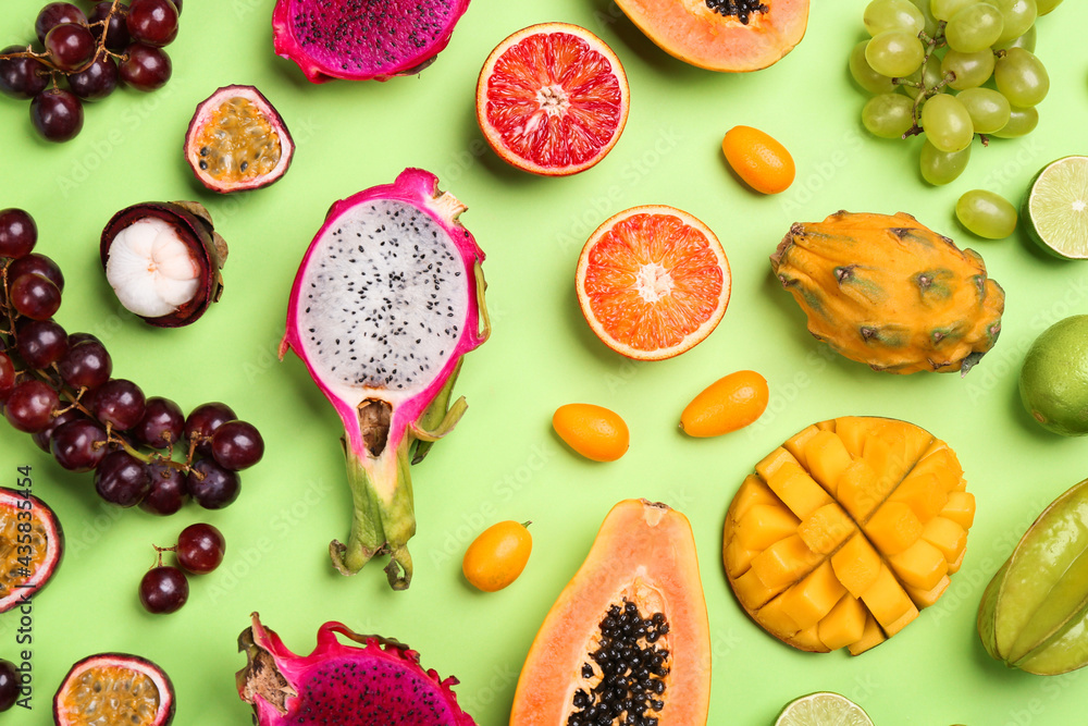 Many different delicious exotic fruits on green background, flat lay