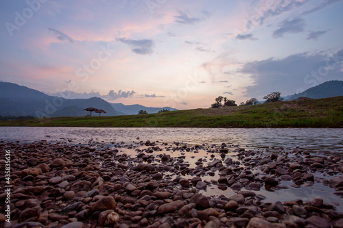 Wide view, low angle view, riverside scenery, mountains, evening sky, falling summer river, see small boulders