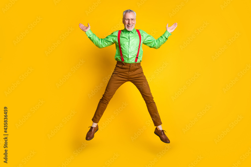 Full size photo of senior man happy positive smile active jump feel young isolated over yellow color background