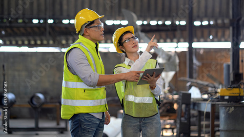 Photographie asian industrial Engineer manager man wearing eyeglass and helmet   discussion with mechanic worker woman while using digital tablet checking industry manufacturing large factory