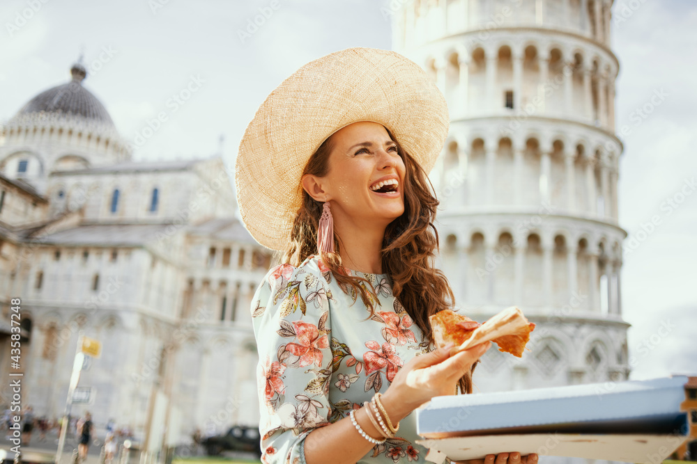 smiling trendy woman in floral dress with pizza and hat