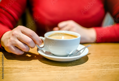 A girl drinks coffee at a table in a cafe 