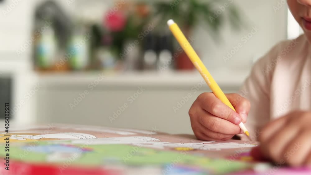 little girl with a pencil in her hands draws, writes, does homework sitting at the kitchen table little girl with a pencil in her hands draws, writes, does homework sitting at the kitchen table