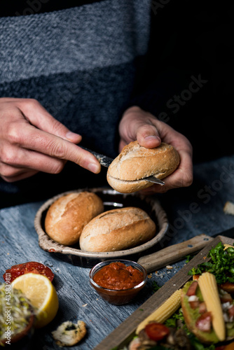 man cuts a bread bun to prepare a sandwich