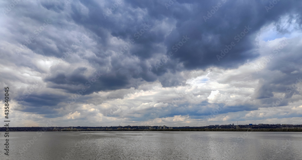 beautiful dark gray clouds are reflected in the river, cloudy spring day, dullness and coolness