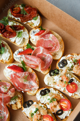  A set of different snacks for a party or a festive table. Ciabatta sandwiches with tomatoes, jamon, cream cheese, vegetables, chambers and olives. Delicious wine snacks