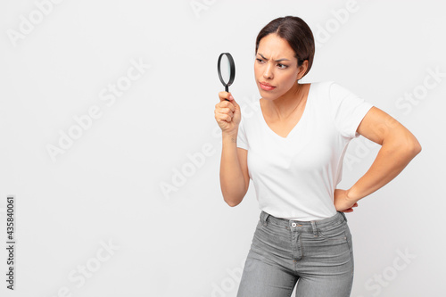 young hispanic woman holding a magnifying glass