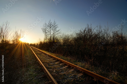 Railroad track in sunset sky with sun.