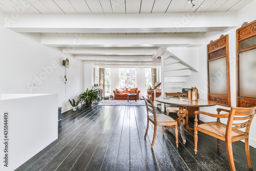 House sun lit room with terracotta sofas and ornamental carpet on wooden floor near staircase leading to second floor photo