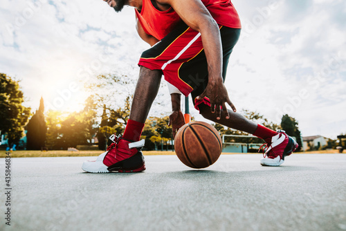 Basketball street player dribbling with ball on the court - Streetball, training and activity concept