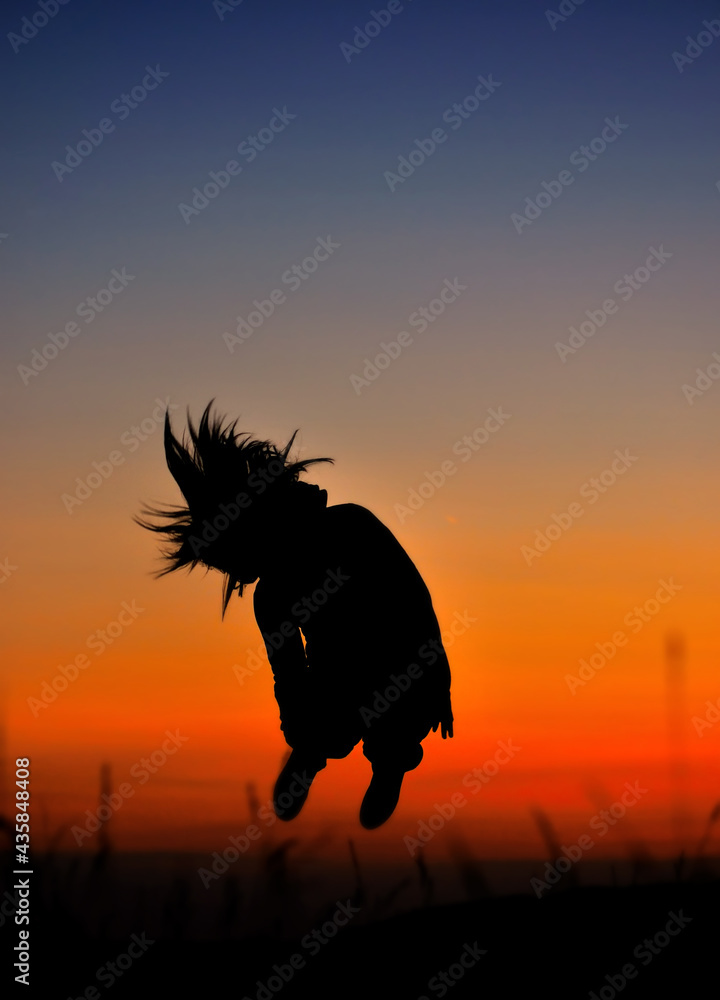 Silhouette of girl jumping in sunset