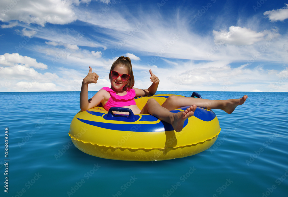  Little girl on inflatable ring in blue sea water