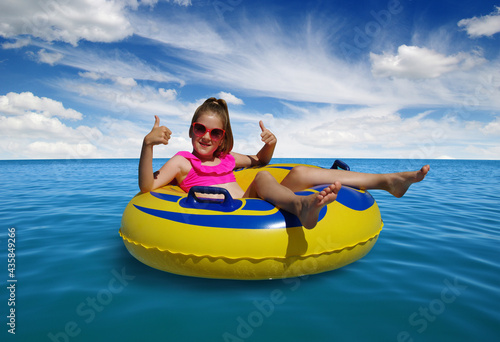  Little girl on inflatable ring in blue sea water