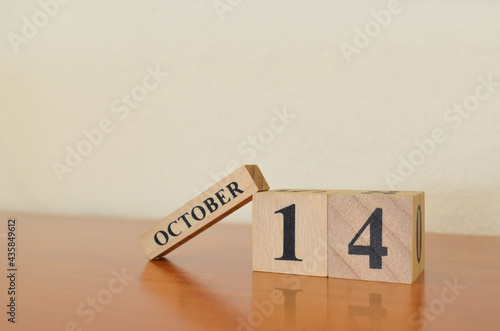 October 14, Date design with calendar cube on wooden table and white background.