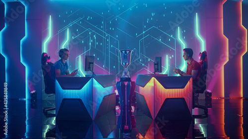 Two Professional Esport Gamers Using Controllers Playing Console Video Games on a Championship Event with Big TV Screens and Stylish Neon Arena. Global Online Streaming Cyber Gaming Tournament