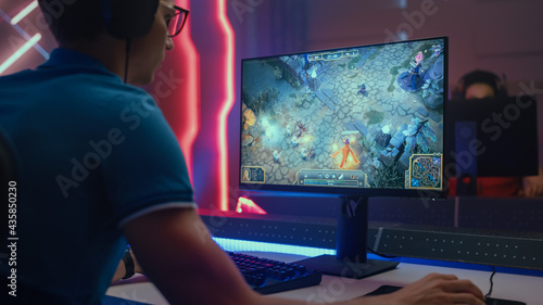 Photography Professional eSports Gamer Plays RPG MOBA Mock-up Video Game with Super Action and Fun Special Effects on His Personal Computer, Talks to Teammates using Headset