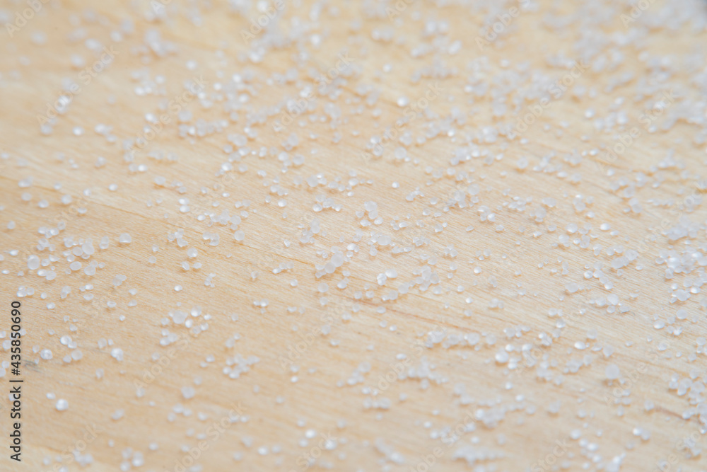 Background with salt scattered on a wooden surface. Close-up of blurry salt granules in soft focus at high magnification. Background with salt scattered on a wooden surface. Close-up of blurry salt granules in soft focus at high magnification.
