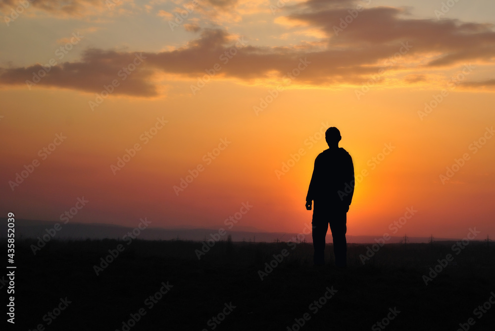 Boy silhouette standing in the sunset