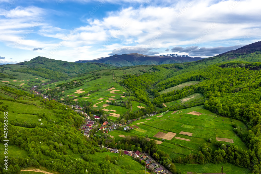 Snow-capped mountain peaks and beautiful forest mountains in summer aerial view.