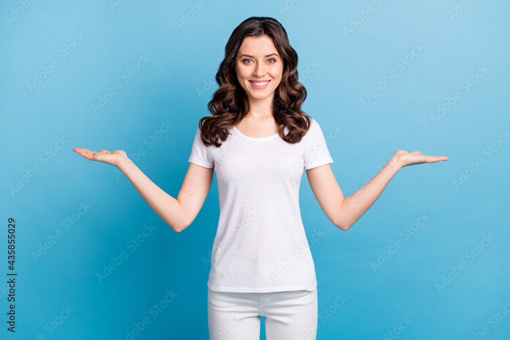 Photo of pretty sweet young woman wear white t-shirt showing arms scales holding empty space isolated blue color background Photo of pretty sweet young woman wear white t-shirt showing arms scales holding empty space isolated blue color background