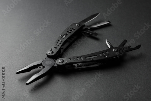 Obraz na plátne Compact portable multitool on black background, closeup