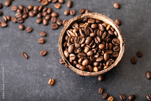 black coffee beans arabica, aromatic in a coconut bowl, sprinkled beans on the table