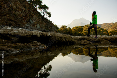 wonderful view of water of mountain lake and young woman tourist standing near it