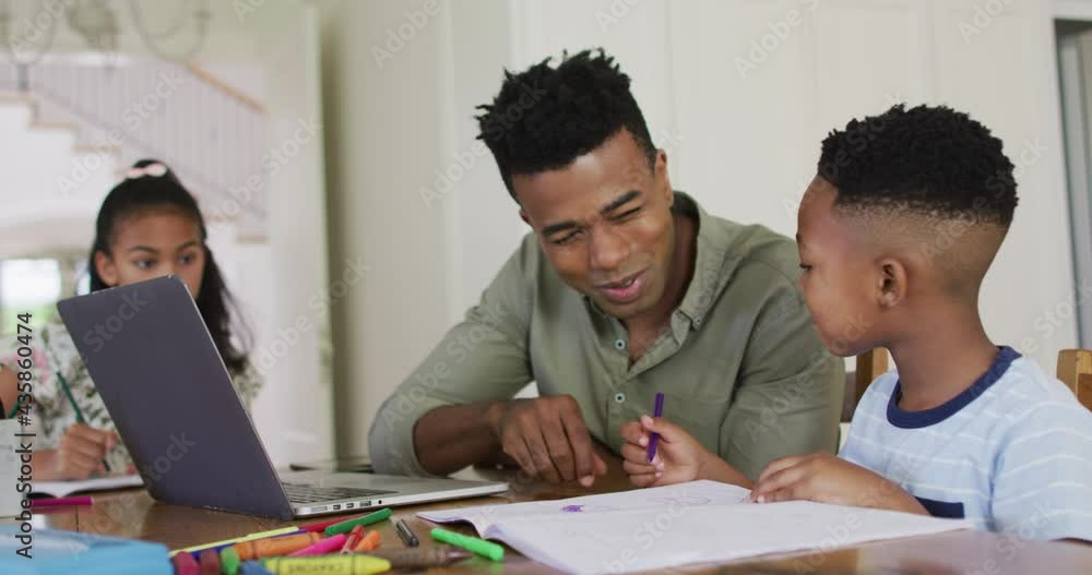 African american father, daugher and son sitting at kitchen table doing homework African american father, daugher and son sitting at kitchen table doing homework