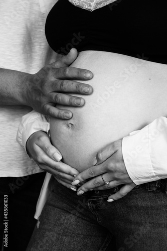 Parents' hands lie on the belly of the pregnant woman. Young parents expecting a baby