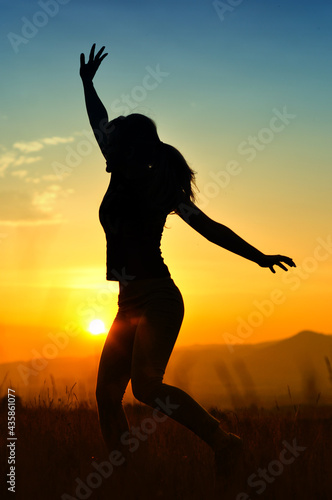 Silhouette of girl jumping in sunset