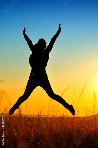 Silhouette of girl jumping in sunset