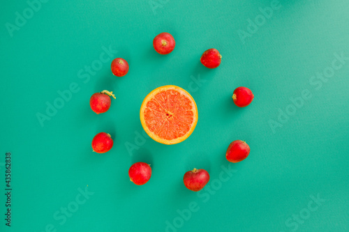 Sun of radishes and oranges on a blue-green pastel background. Summer fruits and vegetables. Symbol of the sun.