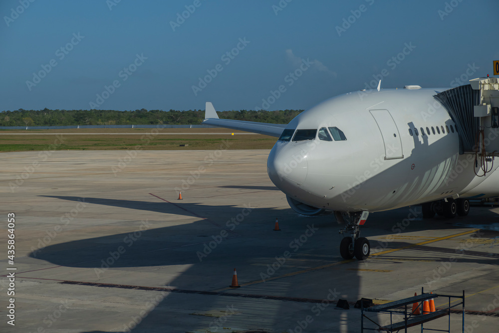 Airplane parked at the airport and connected to the sleeve prior to boarding. Aircraft industry and air transport travel concept. Airplane parked at the airport and connected to the sleeve prior to boarding. Aircraft industry and air transport travel concept.