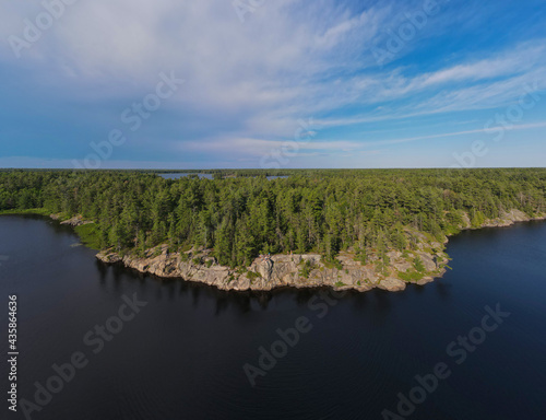 Aerial panorama of a fresh water lake surrounded by rugged rocky cliffs and endless green boreal coniferous forest. Northern Ontario, Canada.