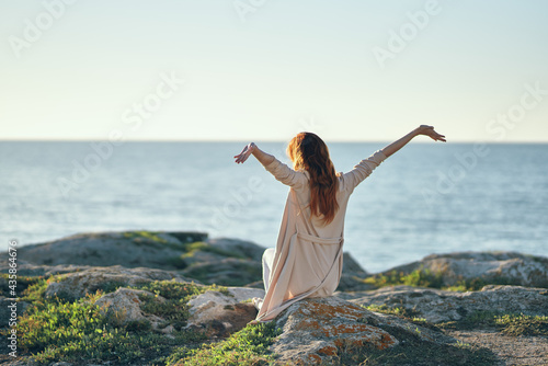 woman with raised up hands on nature in the mountains outdoors near the sea