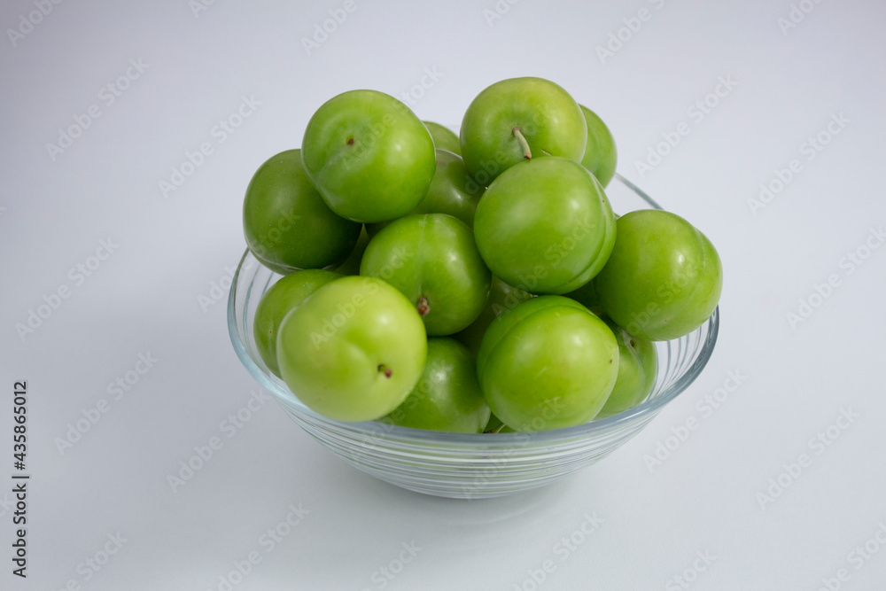 Fresh green plums in a glass bowl on white background. Fresh green plums in a glass bowl on white background.
