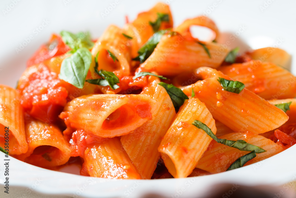 Piatto di deliziose penne rigate con sugo di pomodoro biologico e basilico Piatto di deliziose penne rigate con sugo di pomodoro biologico e basilico