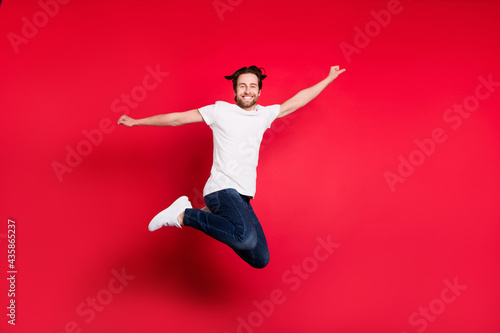 Full body profile side photo of young man happy positive smile jump up excited rejoice isolated over red color background